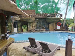 a swimming pool with two chairs and a bench at Coastal Haven Resort in Siquijor
