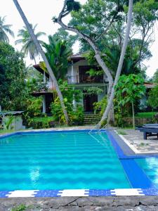a swimming pool in front of a house at Priyanka Villa in Bentota