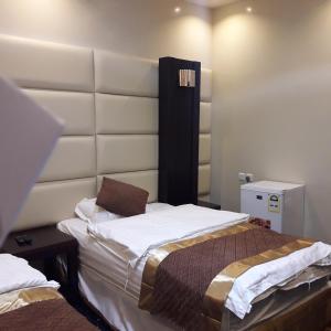 a bedroom with a large bed with a white headboard at اجواء المساء للشقق المخدومة in Wadi Al Dawasir