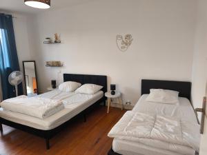 two beds in a room with white sheets at Maison familiale in Orleix