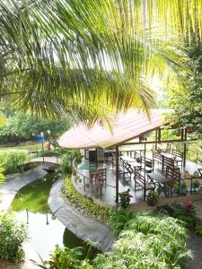 a restaurant with tables and a pond and a palm tree at Tamarind Retreat in Alibaug