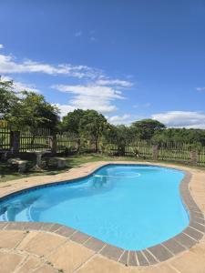 a blue swimming pool in a yard with a fence at Intibane Lodge in Ulundi