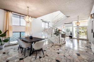 a living room with a table and chairs and stairs at Comfortable House-shared accommodation in Bankstown +1 photo