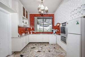 a kitchen with white cabinets and a window at Comfortable House-shared accommodation in Bankstown