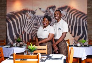 a man and woman standing in front of a painting of zebras at Intibane Lodge in Ulundi +122 photos
