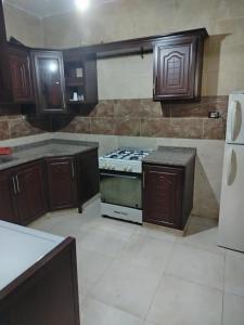 a kitchen with wooden cabinets and a stove at الشقة العائلية الحديثة familial new flat in Amman