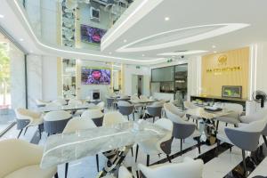 a restaurant with white chairs and tables in a room at NaCo Hotel in Lao Cai