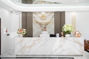 a woman standing behind a counter in a lobby at NaCo Hotel in Lao Cai