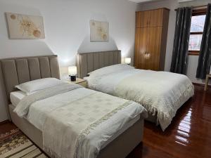 two beds sitting next to each other in a bedroom at Bujtina Kenedi in Korçë +3 photos