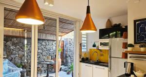 a kitchen with two pendant lights and a stone wall at The loft - A charming sanctuary in Rivière Noire
