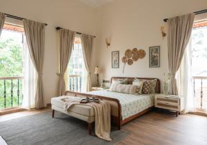 a bedroom with a large bed and large windows at LohonoStays Villa Floresta in Assagao