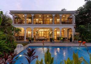 an exterior view of a mansion with a swimming pool at LohonoStays Villa Floresta in Assagao
