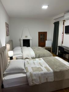 a bedroom with two beds and a fireplace at Bujtina Kenedi in Korçë