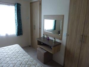 a bedroom with a bed and a dresser with a mirror at Shrimp Shack in Heysham +56 photos