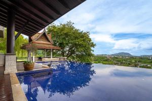 a swimming pool with a view of a house at Royal Legacy Golf Private Villa in Rawai Beach