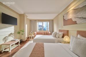 a hotel room with two beds and a couch at Silverland Jolie Hotel in Ho Chi Minh City