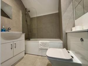 a bathroom with a toilet and a sink and a tub at Egham Modern Two Bedroom Apartment in Egham +6 photos