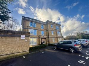 a car parked in a parking lot in front of a building at Egham Modern Two Bedroom Apartment in Egham