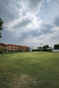 a large grass field with buildings in the background at Udaigarh Palace - The Heritage Hotel in Jodhpur