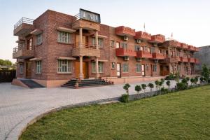 a large red brick building with a lawn in front of it at Udaigarh Palace - The Heritage Hotel in Jodhpur +4 photos