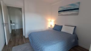 a bedroom with a bed with a blue comforter and a lamp at Coimbra's Black & White in Coimbra