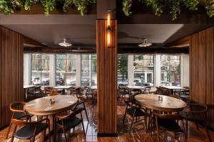 a restaurant with wooden tables and chairs and windows at Hotel 1935- By Adam Hotels in Tel Aviv