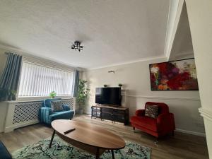 a living room with two chairs and a tv at Spacious 5 Bedroom House Addlestone in Addlestone
