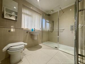a bathroom with a shower and a toilet and a sink at Spacious 5 Bedroom House Addlestone in Addlestone +16 photos