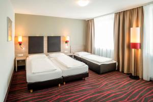 a hotel room with two beds and a desk at Europäischer Hof in Munich