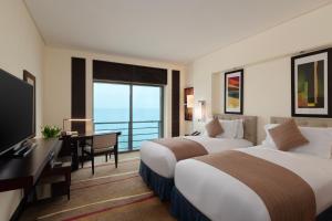a hotel room with two beds and a desk and a television at Sofitel Al Khobar The Corniche in Al Khobar