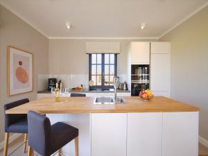 a kitchen with white cabinets and a wooden counter top at Reetland am Meer - LuxusPlus Reetdachvilla mit 4 Schlafzimmern, Außensauna, Loungebereich und Kamin H09 in Dranske