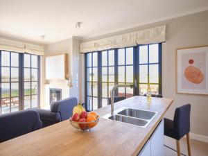 a kitchen with a sink and a bowl of fruit on a counter at Reetland am Meer - LuxusPlus Reetdachvilla mit 4 Schlafzimmern, Außensauna, Loungebereich und Kamin H09 in Dranske +13 photos