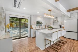 a kitchen with white cabinets and a large island with bar stools at Redwoods Luxury Sanctuary in Redway