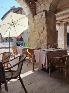 an outdoor patio with tables and chairs and an umbrella at au coin perdu in Lauzerte