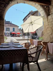 a table and chairs with an umbrella in an archway at au coin perdu in Lauzerte