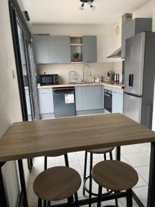 a kitchen with a wooden table and two stools at Évasion du lagon, Le patio de la plage St Pierre in Saint-Pierre