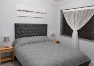 a bedroom with a bed and a window with curtains at At last in Pearly Beach