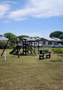 a playground with a swing set and benches in a park at At last in Pearly Beach