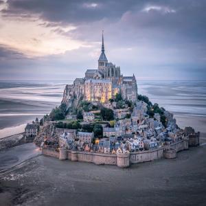 a castle on top of an island in the ocean at Normandy lodges in Le Dézert