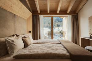 a bedroom with a large bed with a large window at Hotel La Müda in Badia +114 photos