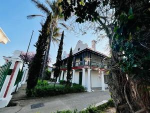 a large white house with a balcony on a street at HEBA GUEST LODGE in Uitenhage