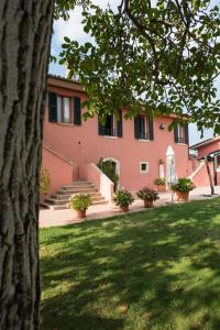 アスコリ・ピチェーノにあるIl Casale Degli Ulivi B&Bの階段と芝生の庭のあるピンクの建物