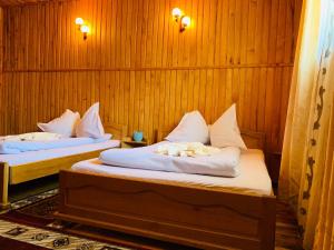 two beds in a room with wooden walls at Casa Andu in Dâmbovicioara +41 photos