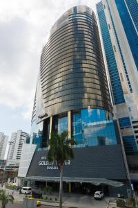 a tall building with a palm tree in front of it at Hotel Las Americas Golden Tower Panamá in Panama City