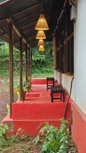 a porch of a house with two benches and a chandelier at Taramrata Homestay in Gokarna