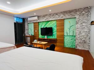 a bedroom with a bed and a tv on a wall at Wind Sea Hill Inn in Hengchun South Gate