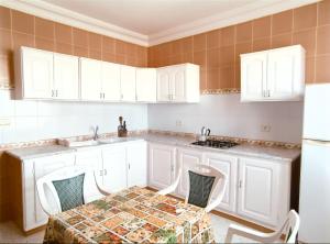 a kitchen with white cabinets and a table and chairs at Sunshine Villa in Gabès