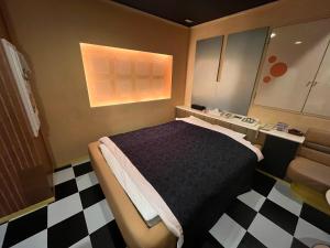 a bedroom with a bed and a checkered floor at ホテル フローレス in Tsubame