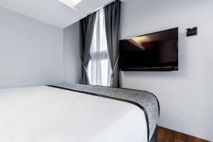 a bedroom with a bed and a flat screen tv at Heritage Collection on Seah - Mobile App Check-In in Singapore