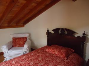 a bedroom with a red bed and a white chair at Ribeirinha House in Porto Formoso